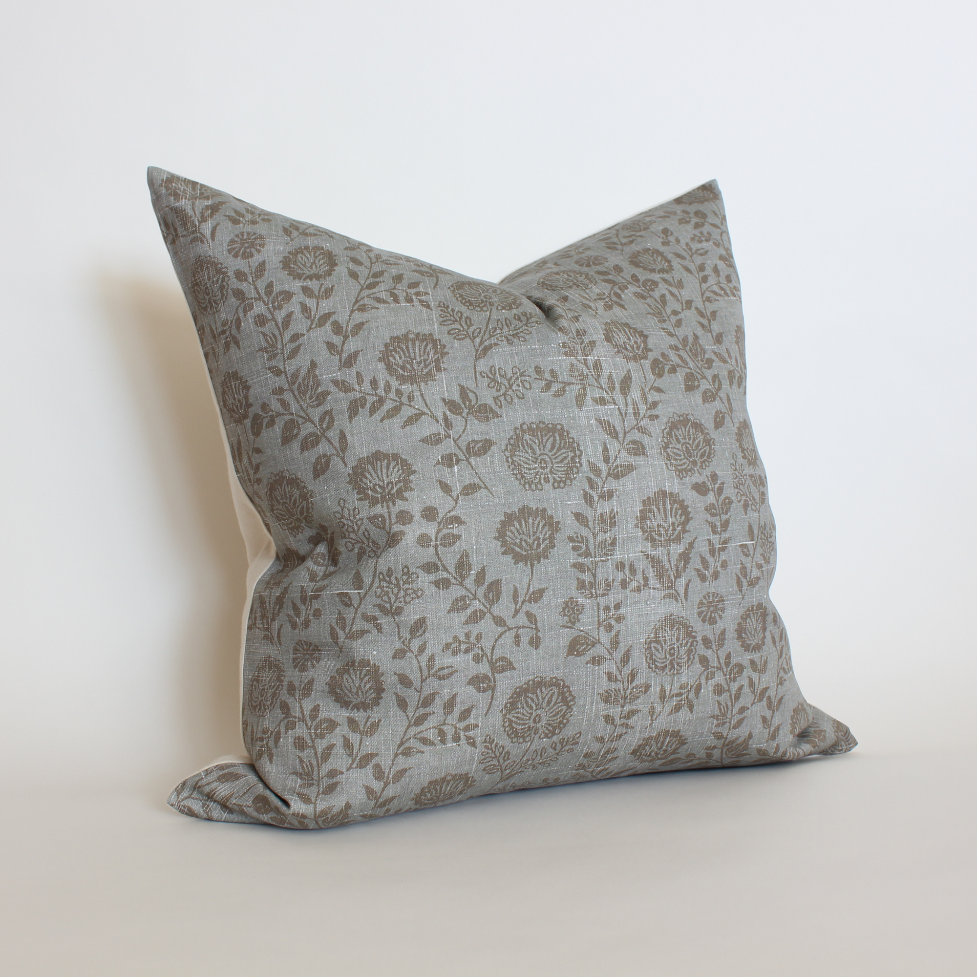 Angled view of blue gray floral pillow cover with taupe botanical vine print, neutral home decor