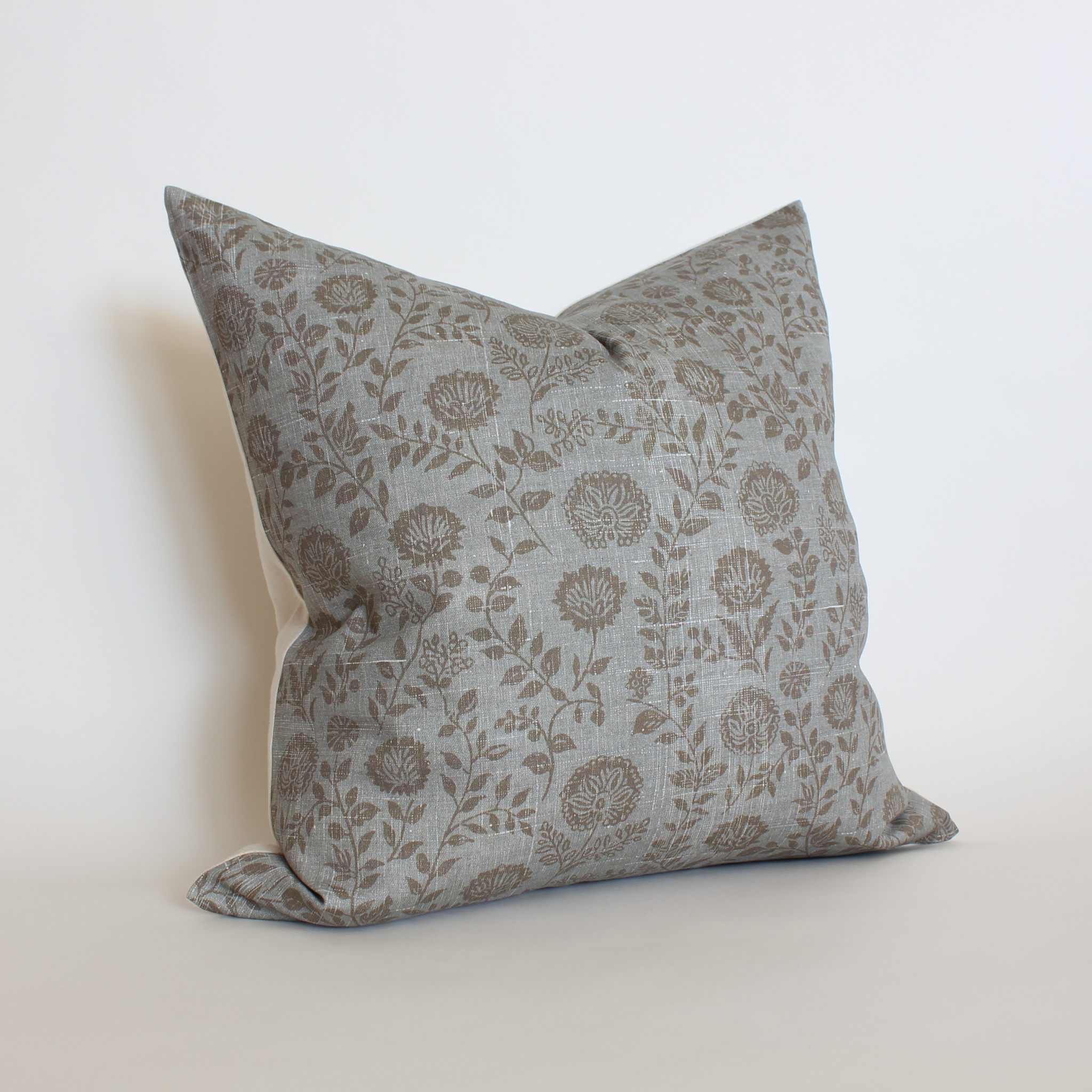tan Floral patterned pillow on a light slate blue background