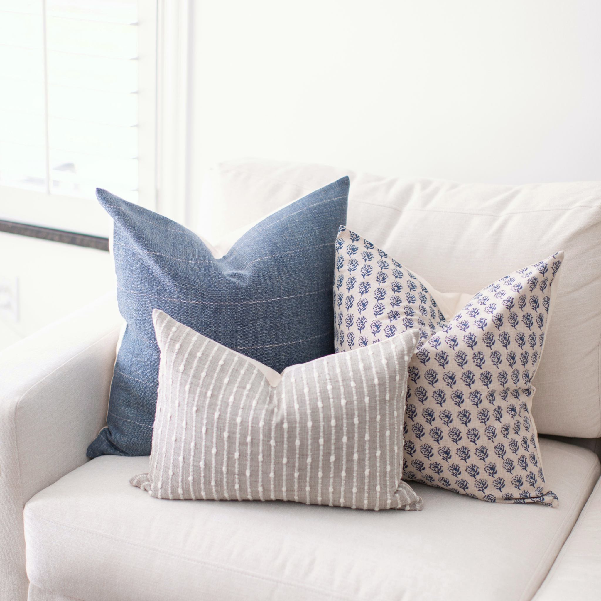 Decorative blue and gray pillows on a white couch with a neutral color scheme
