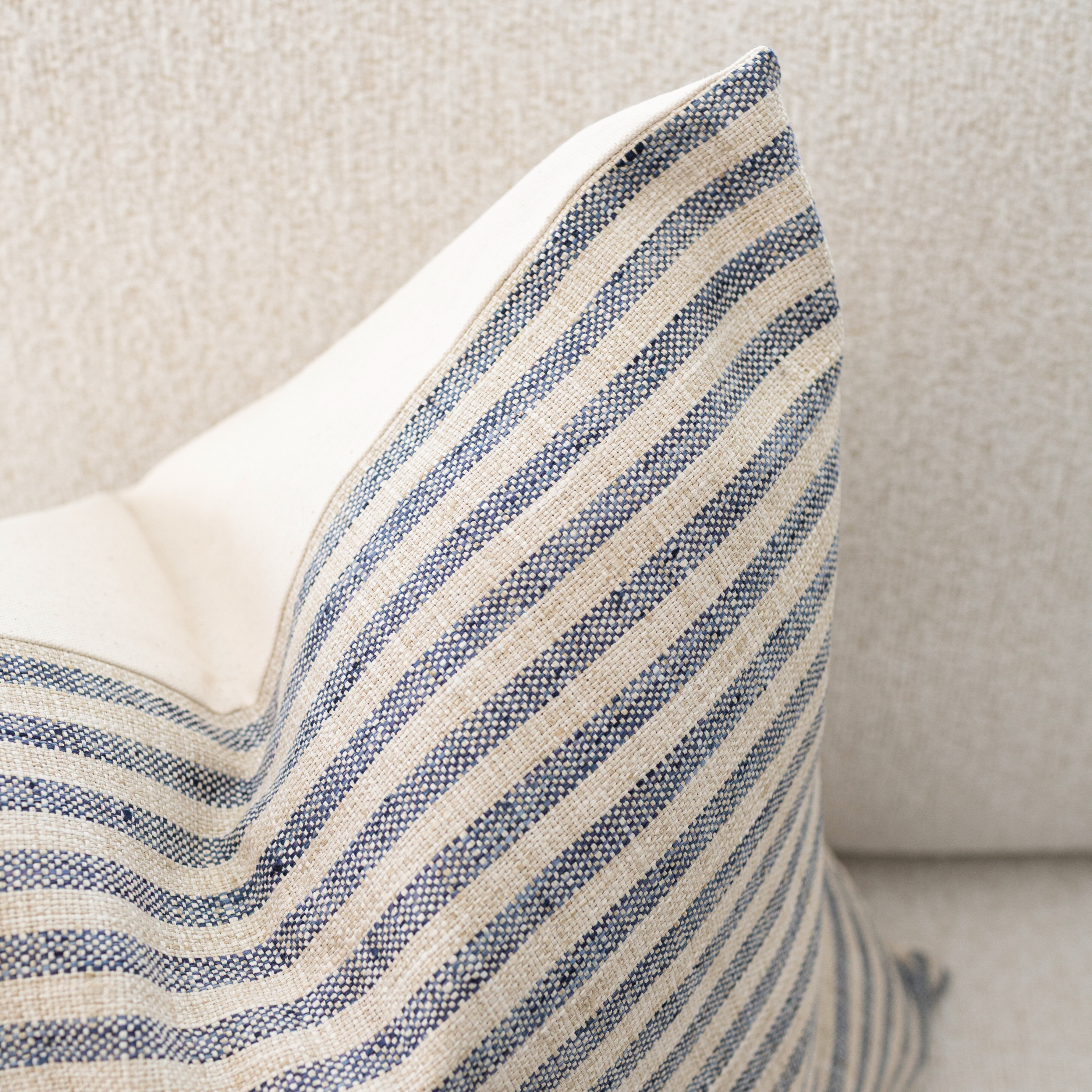 Striped blue and beige pillow on a neutral background
