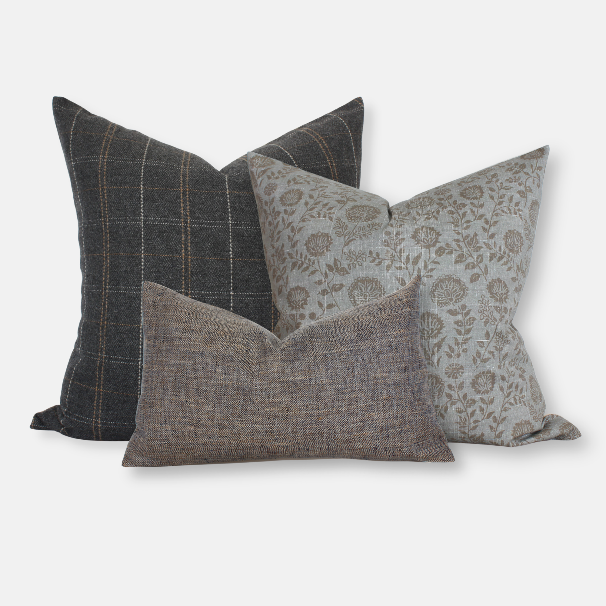 Set of 3 decorative pillow covers in charcoal plaid, slate blue floral block print, and brown herringbone lumbar, styled together