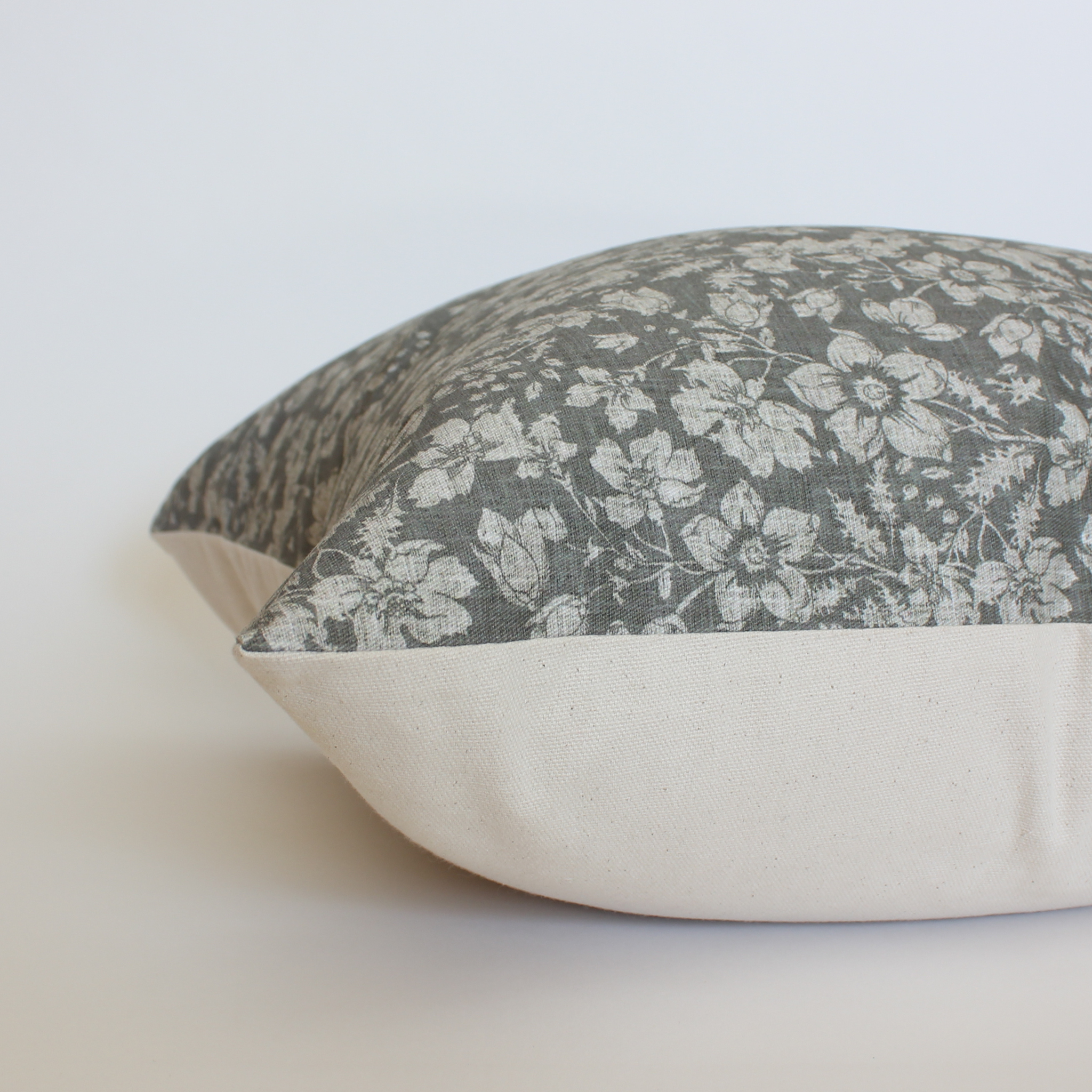 
Side view of dark gray floral throw pillow cover showing cream canvas back and hidden zipper closure