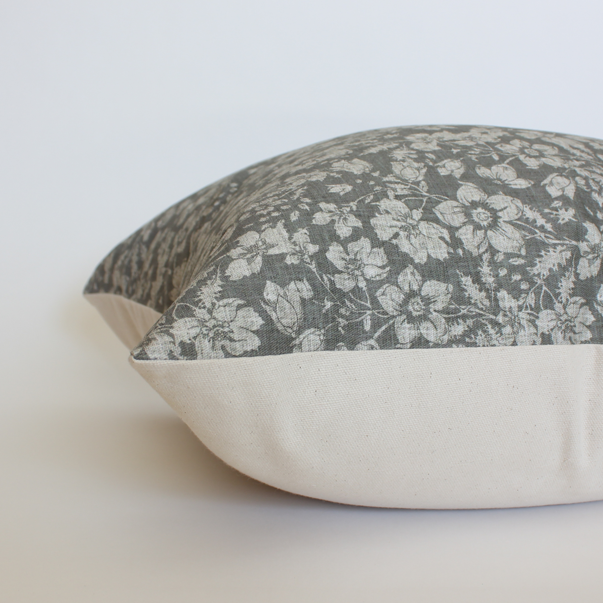 
Side view of dark gray floral throw pillow cover showing cream canvas back and hidden zipper closure