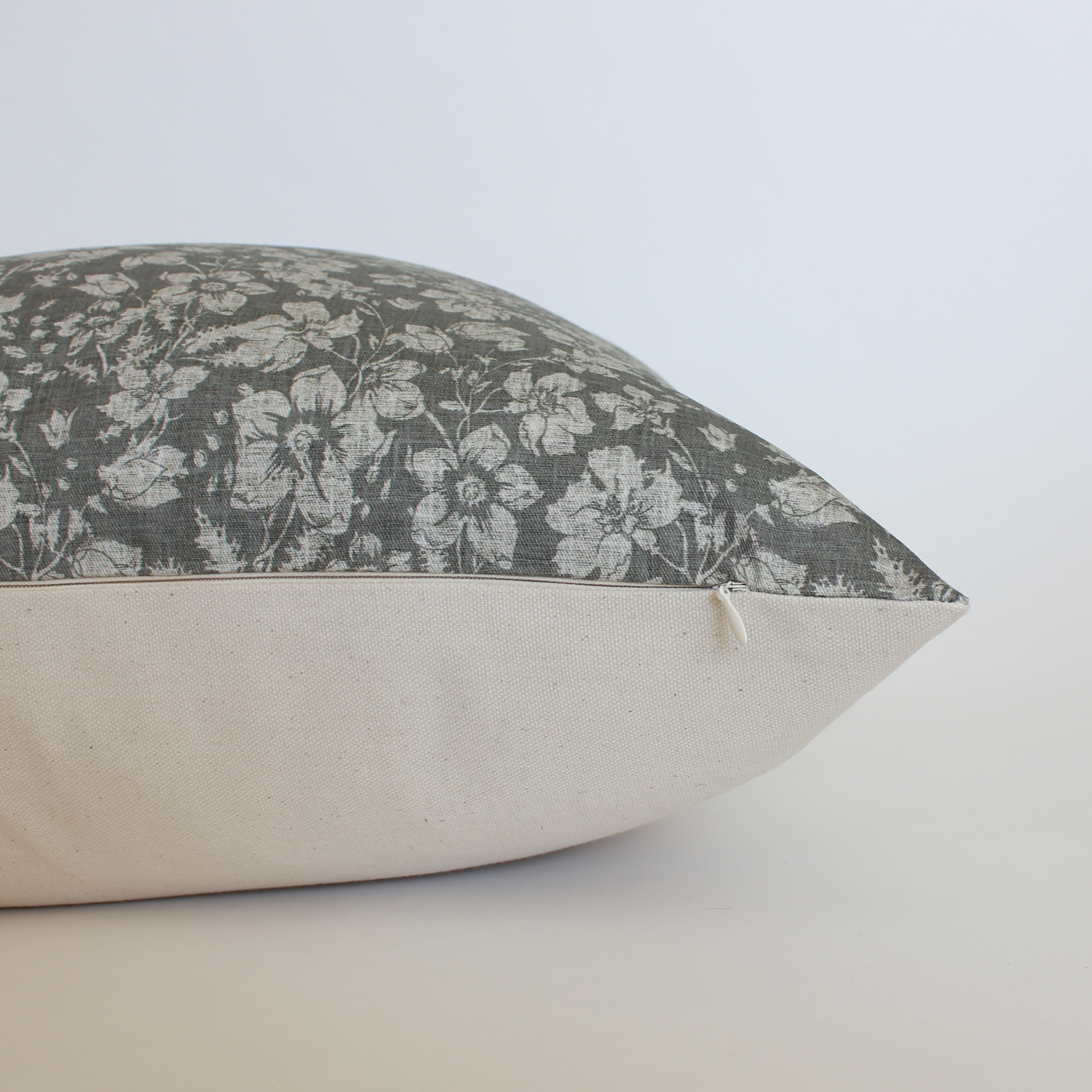 Side view of charcoal botanical lumbar pillow cover showing cream canvas back and zipper closure