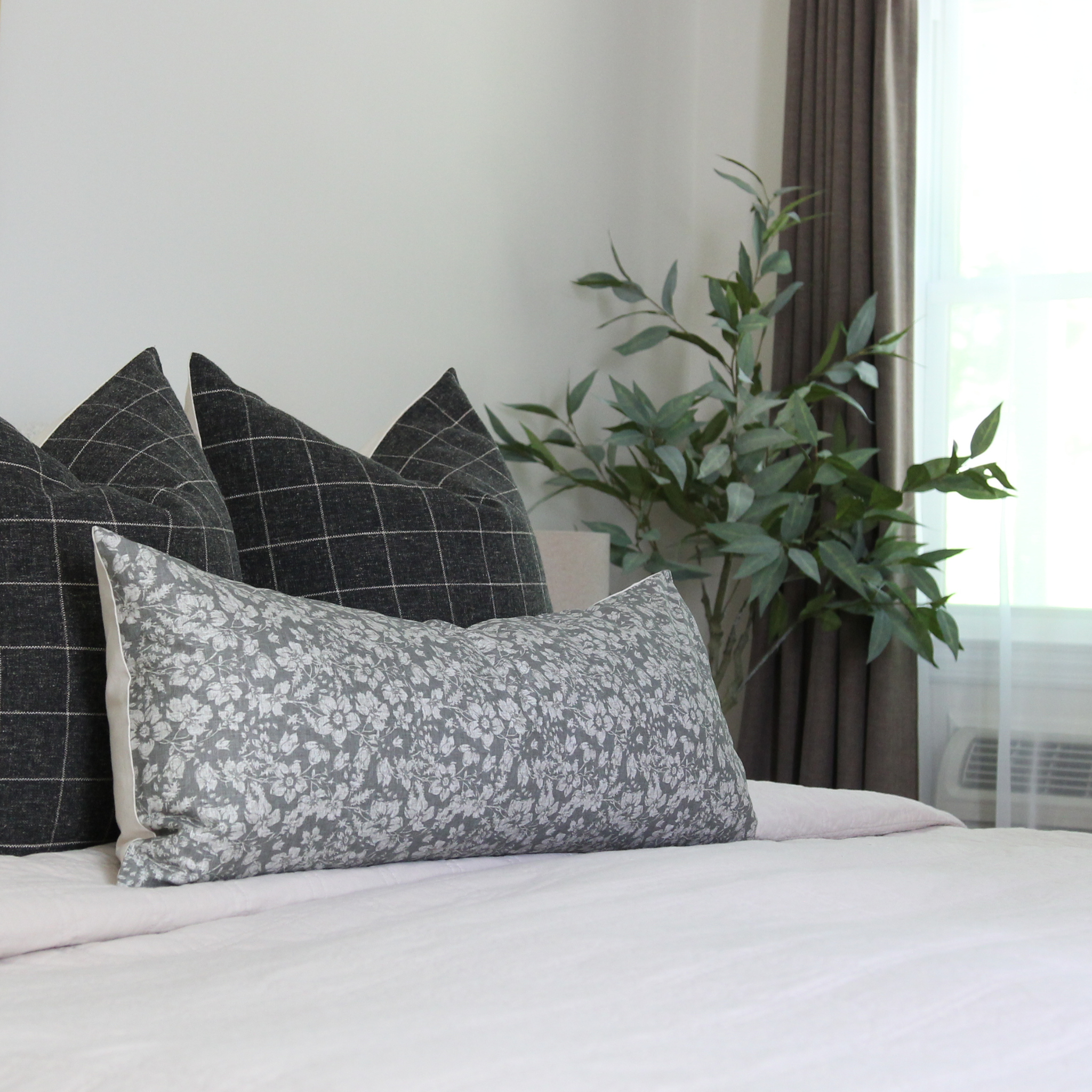 Dark gray botanical lumbar throw pillow styled with plants, quiet luxury bedroom decor