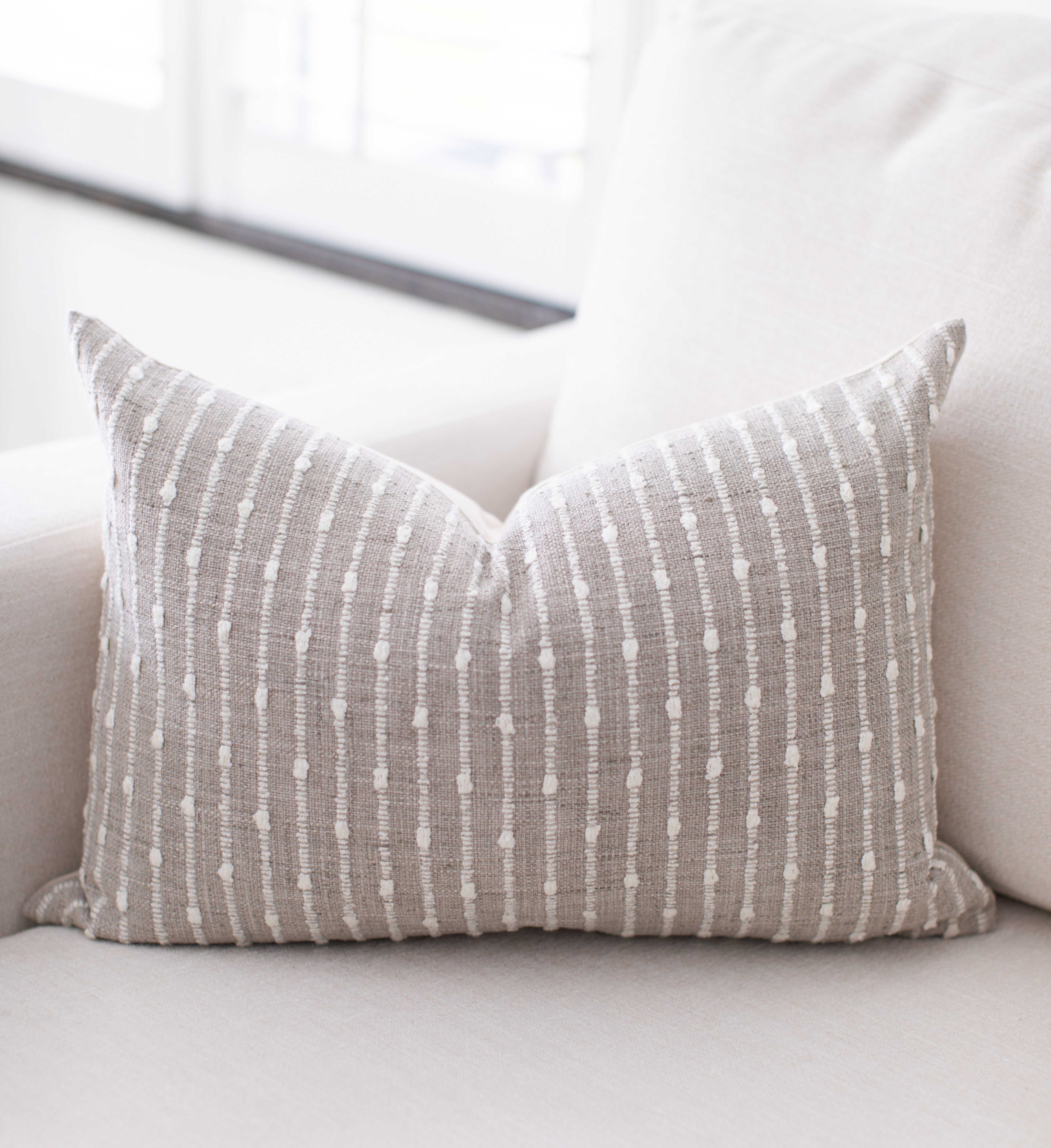 Gray striped pillow with white patterns on a light-colored sofa