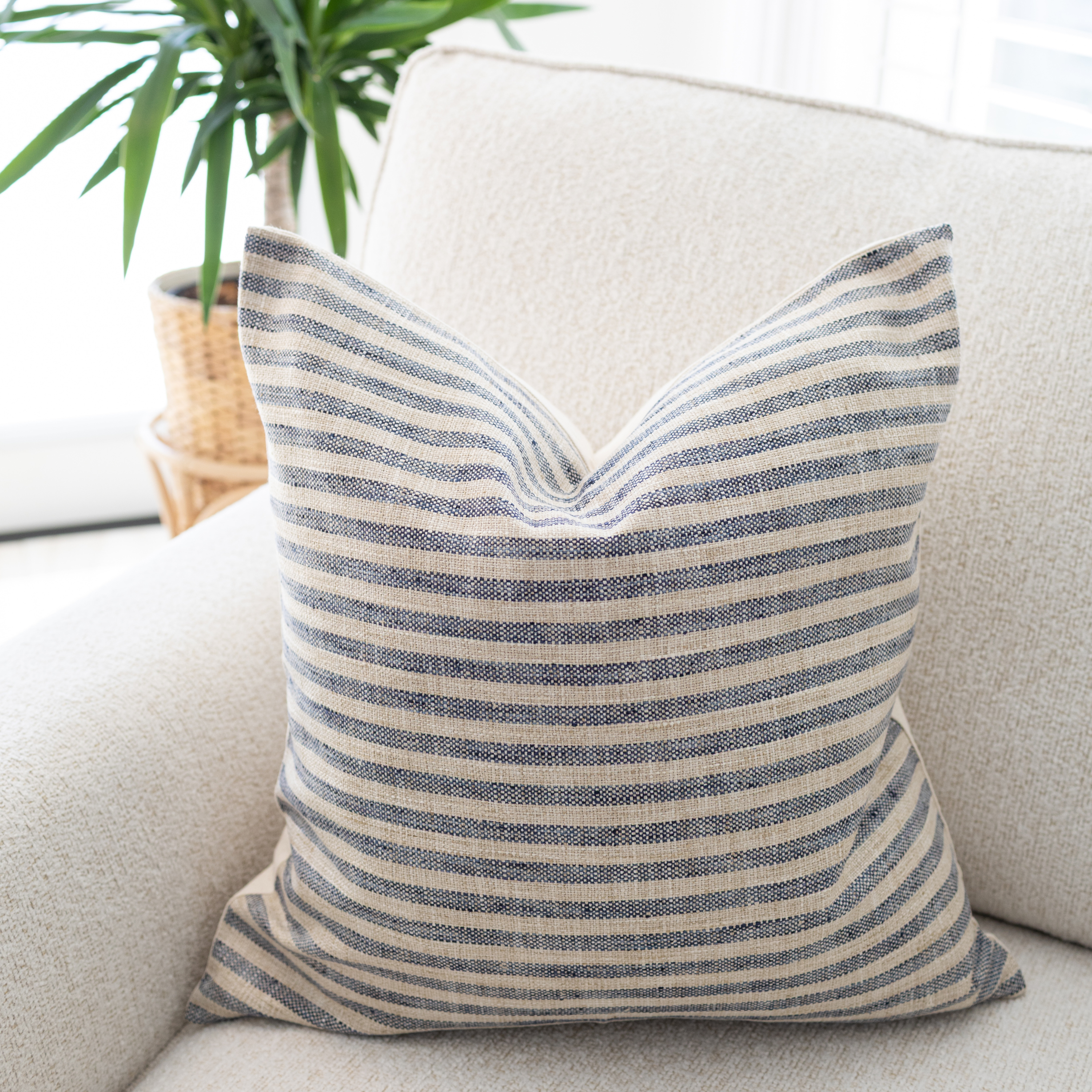 Striped pillow on a beige sofa with a plant in the background