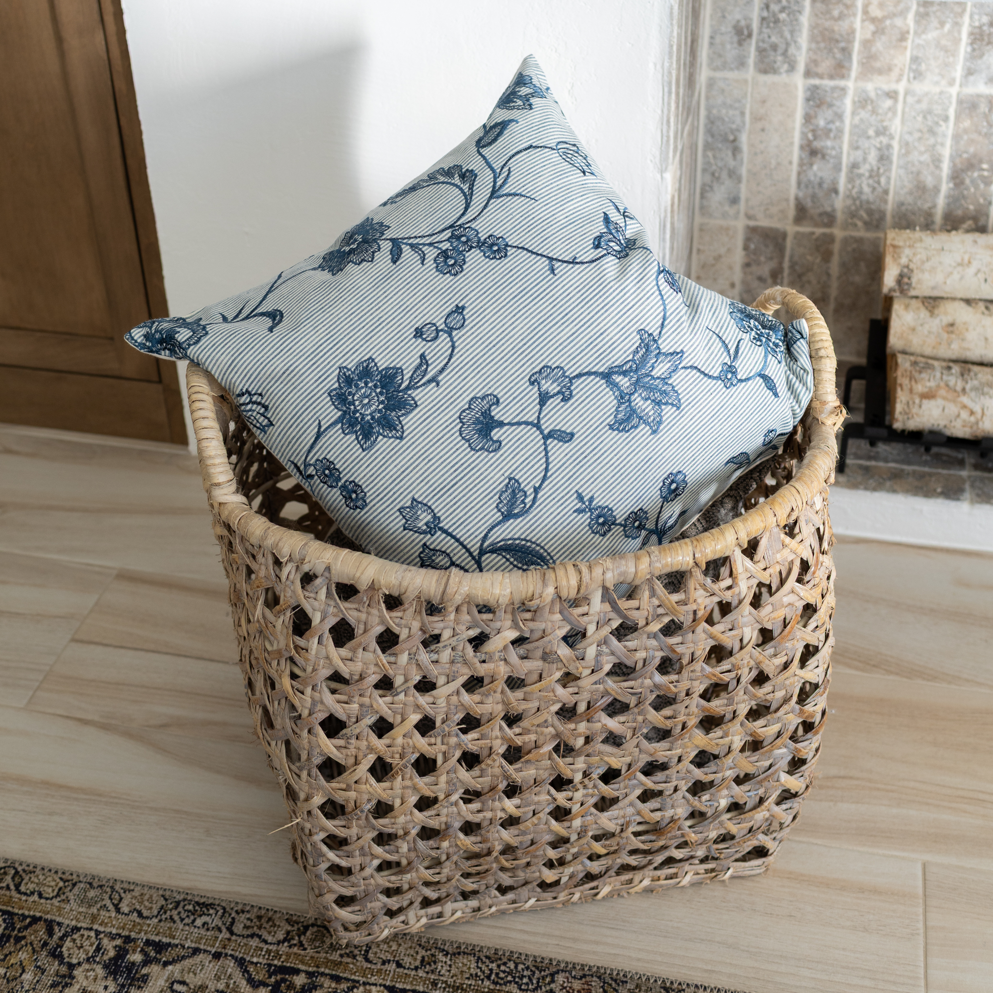 Wicker basket with a floral-patterned pillow on a wooden floor.