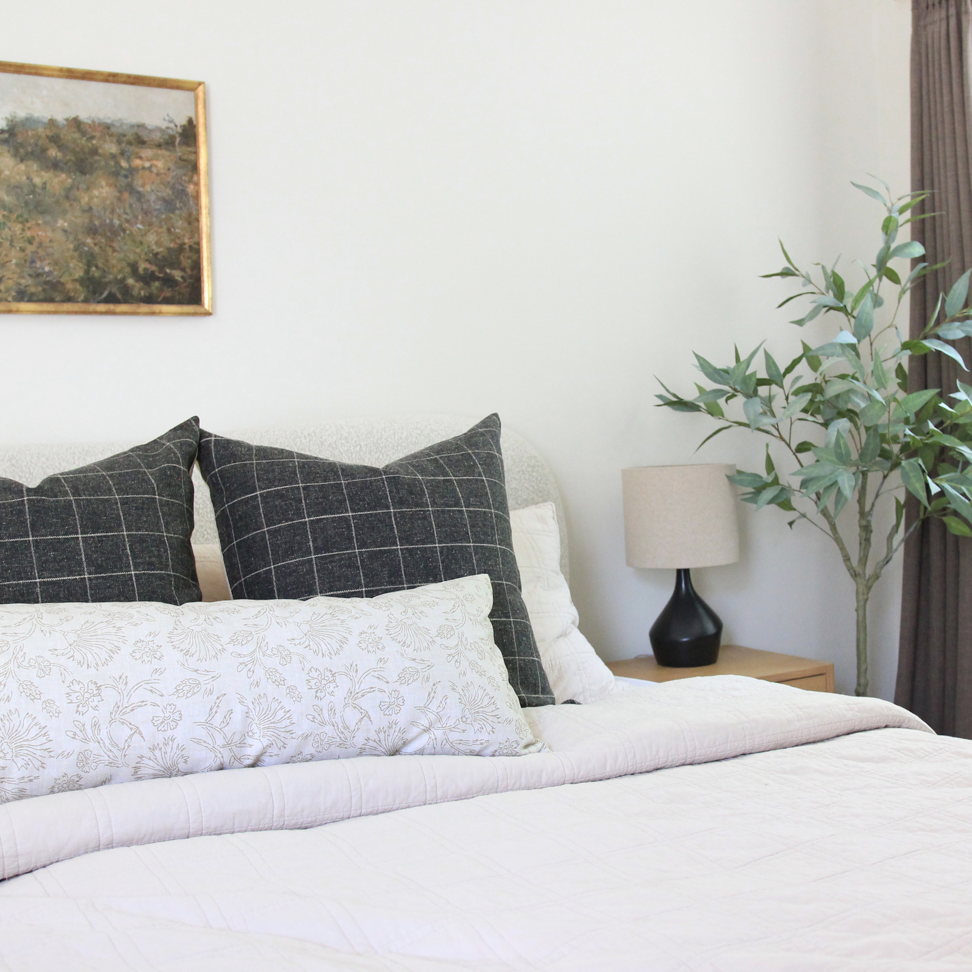 Cream botanical throw pillow styled on bed with neutral bedding, quiet luxury bedroom decor