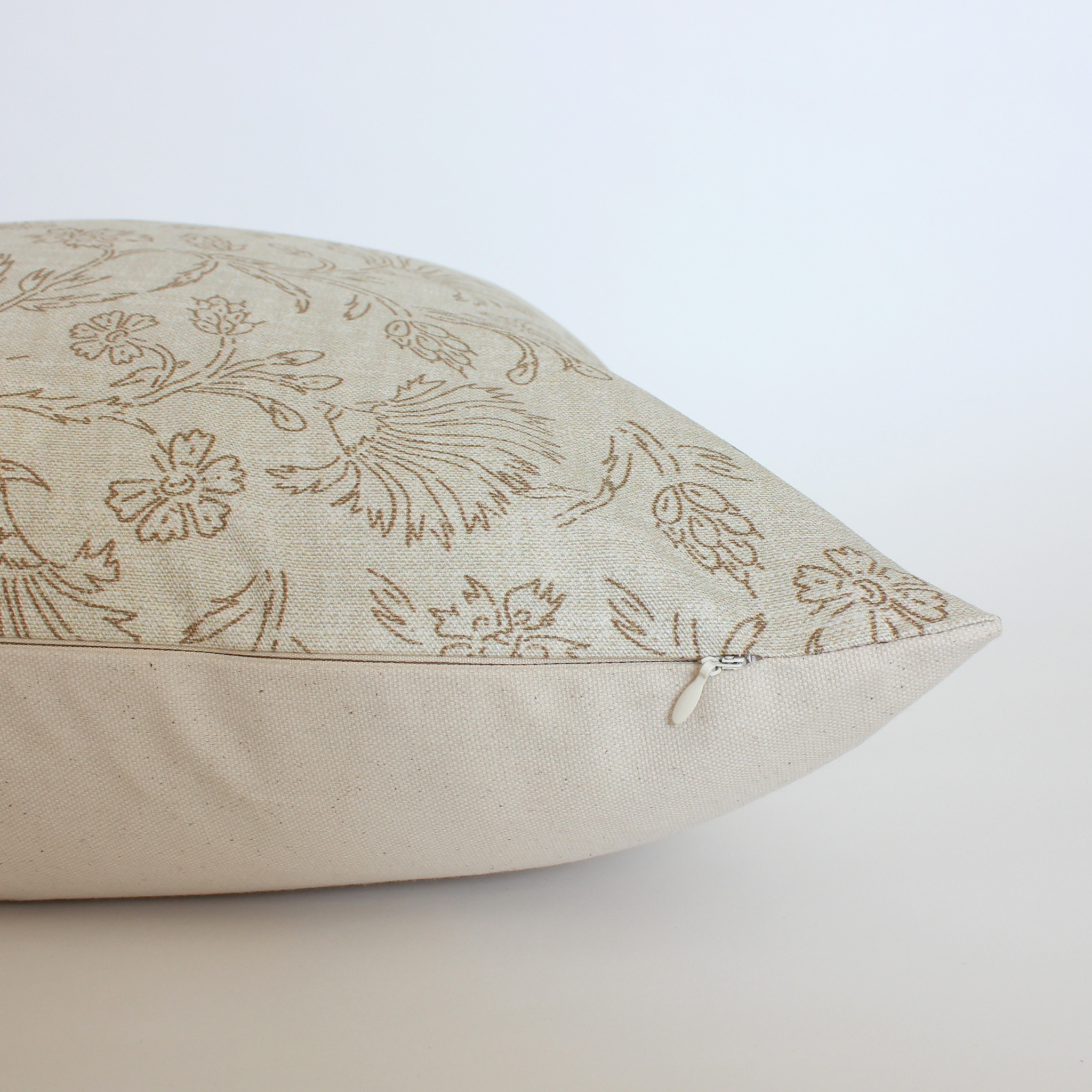 Side view of neutral floral pillow cover showing cream canvas back and hidden zipper closure