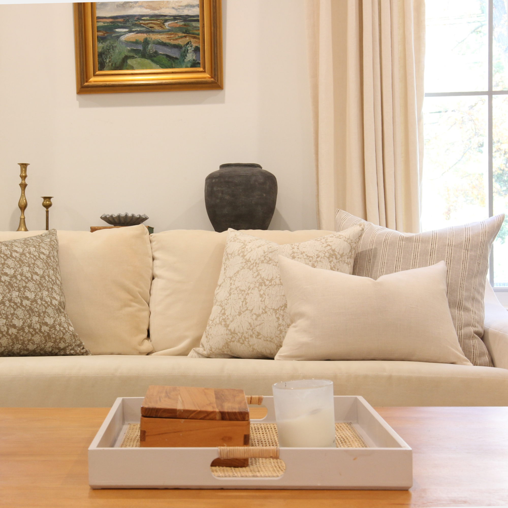 Living room with beige sofa, decorative pillows, and a coffee table with a candle and wooden boxes.