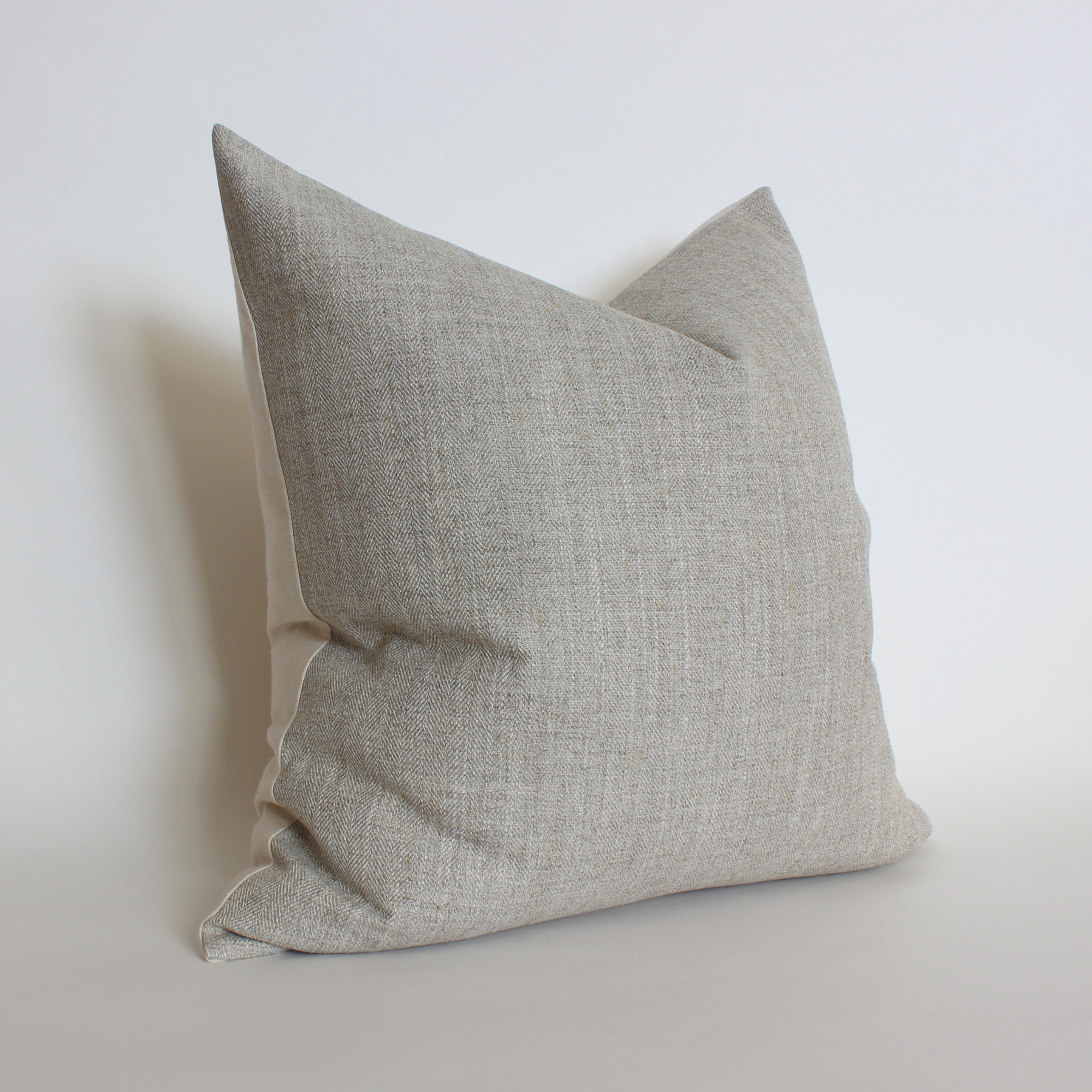 Angled view of neutral herringbone throw pillow cover, coastal home decor accent pillow