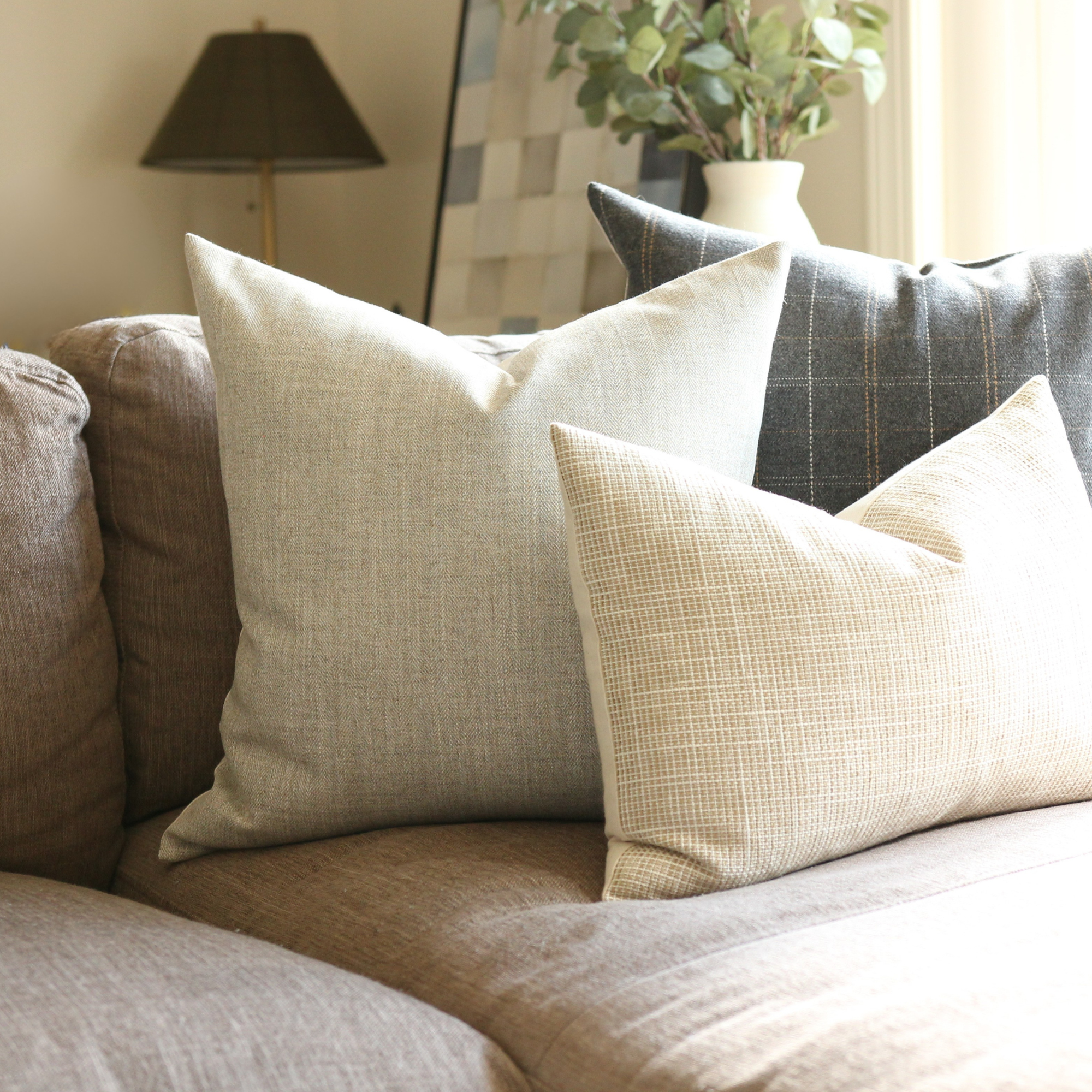 Neutral textured pillow covers styled on tan sofa, quiet luxury living room decor