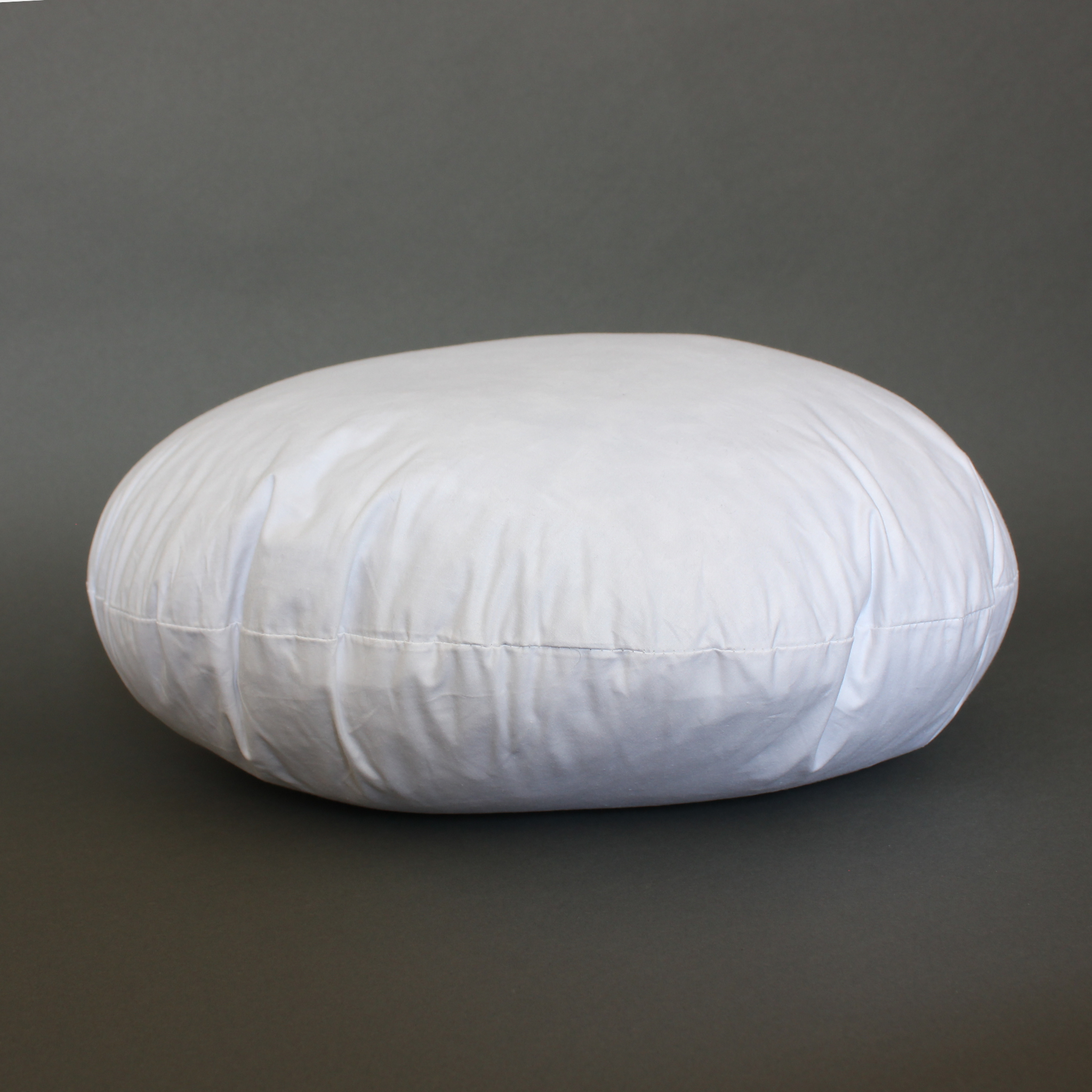 Side view of a round feather pillow insert lying flat, showing thickness and seam