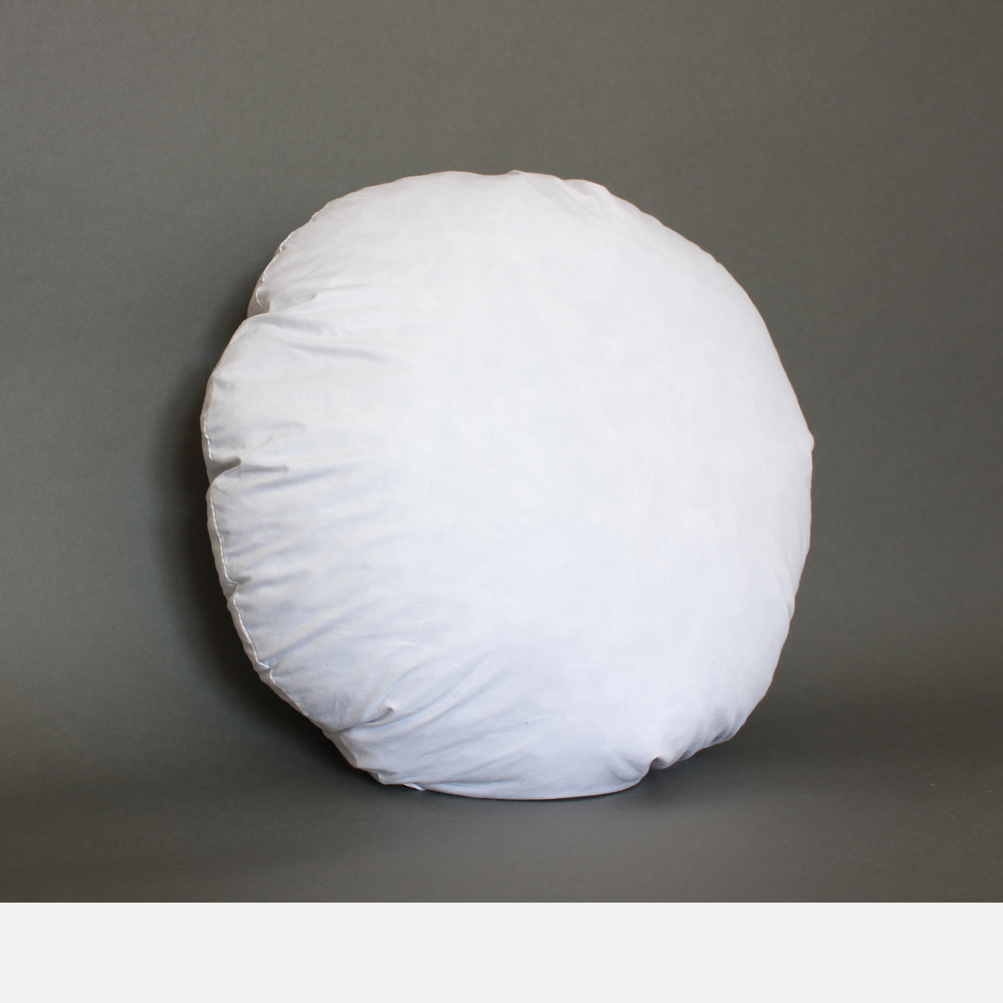 White round feather down pillow insert standing upright on a gray background