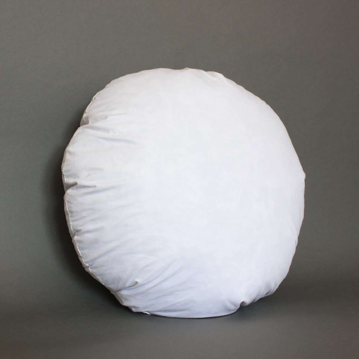 White round feather down pillow insert standing upright on a gray background