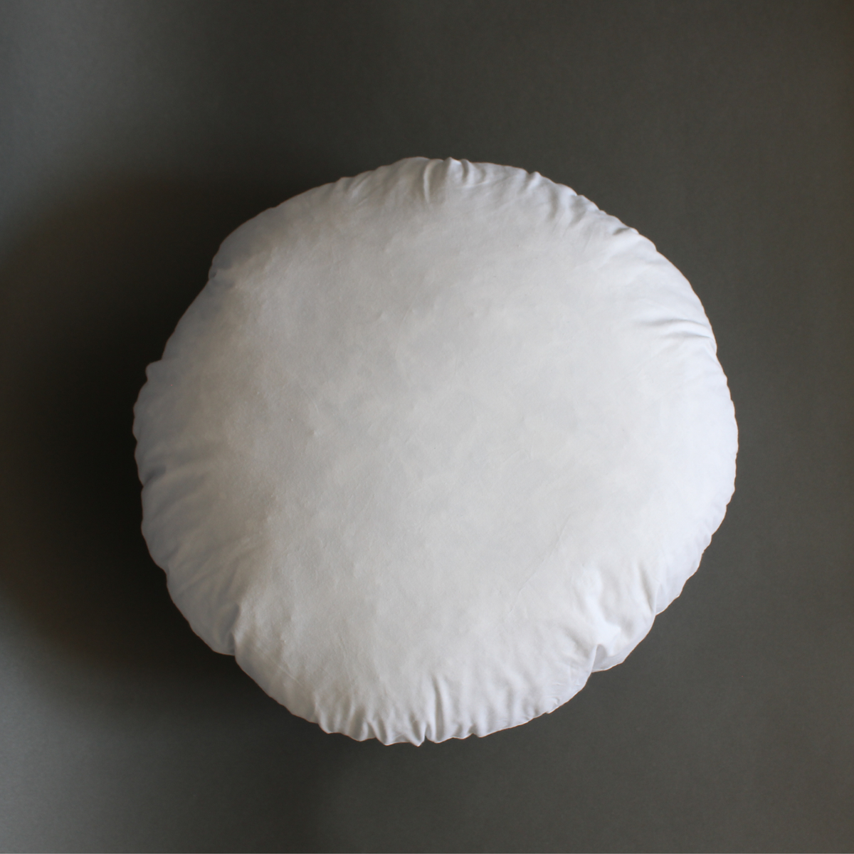 Circle pillow insert with duck feather and down fill, front view on gray background