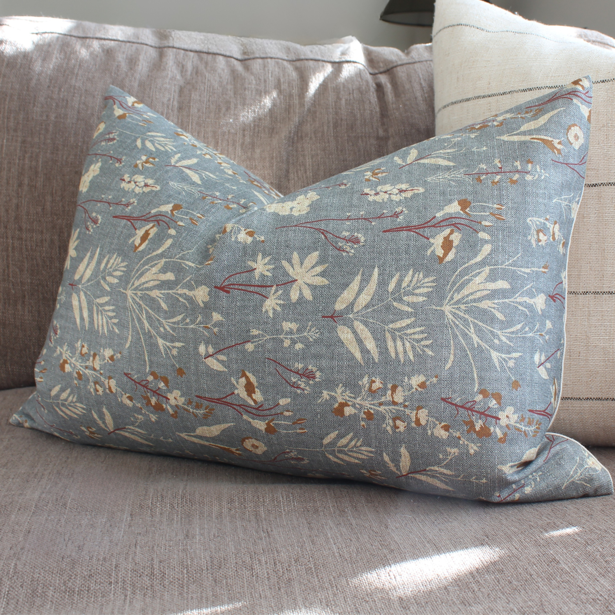 dusty blue Floral-patterned pillow on a brown sofa