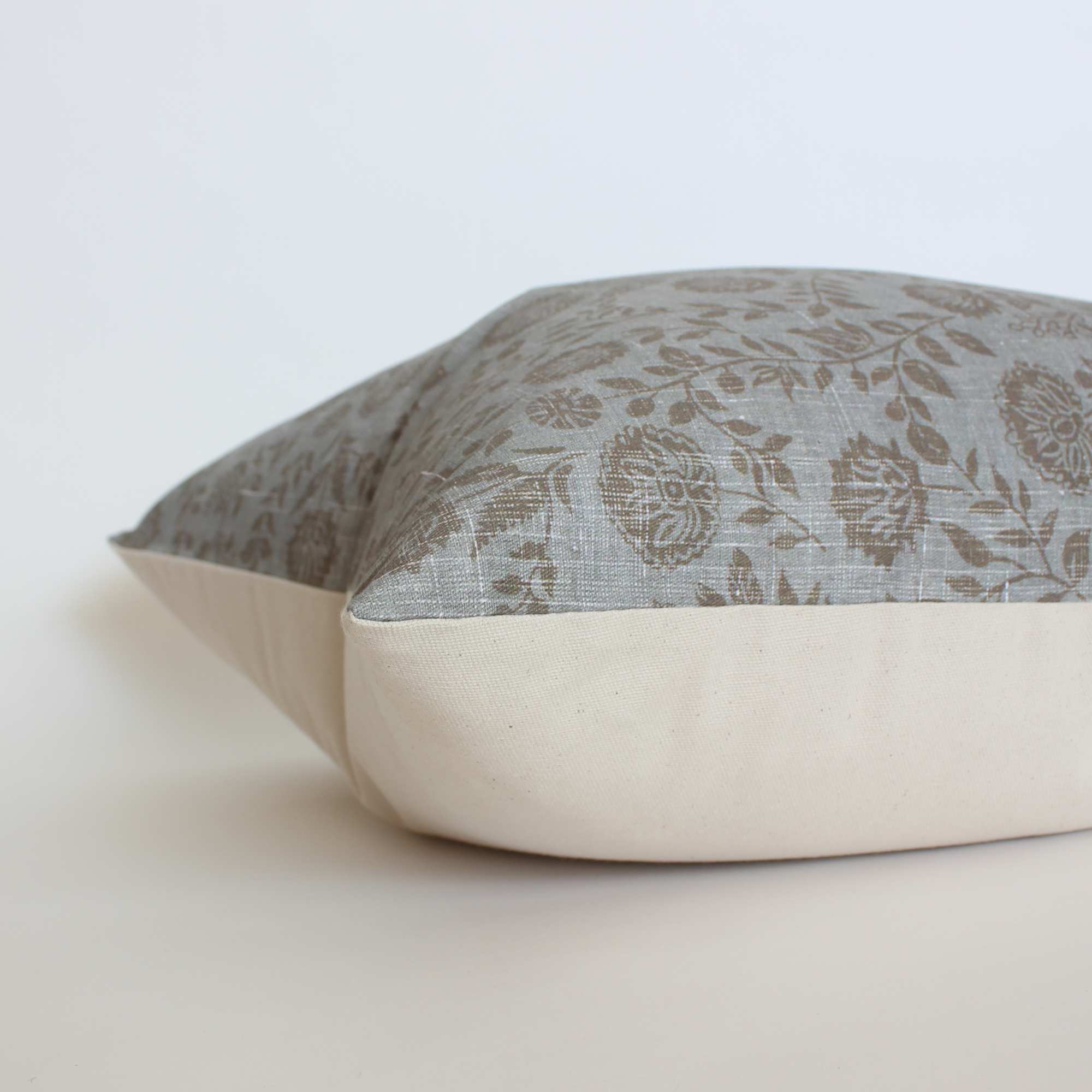 Slate blue floral block print pillow cover, side angle view showing cream fabric back