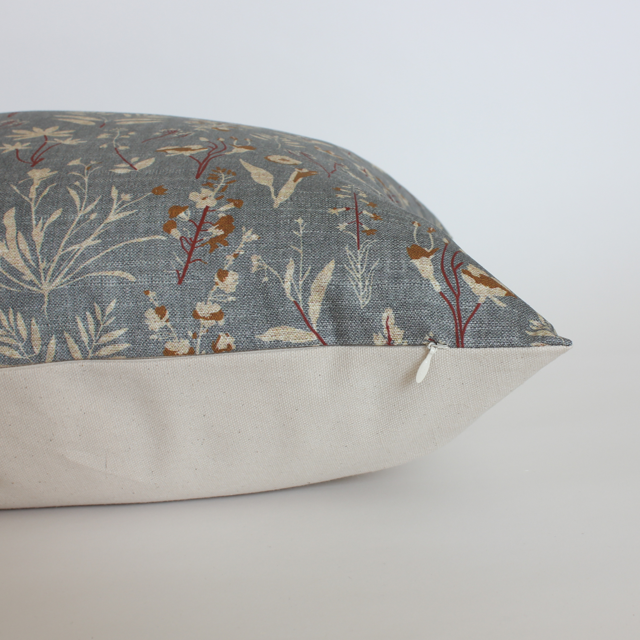 Side view of slate blue floral throw pillow cover showing cream canvas back and hidden zipper closure