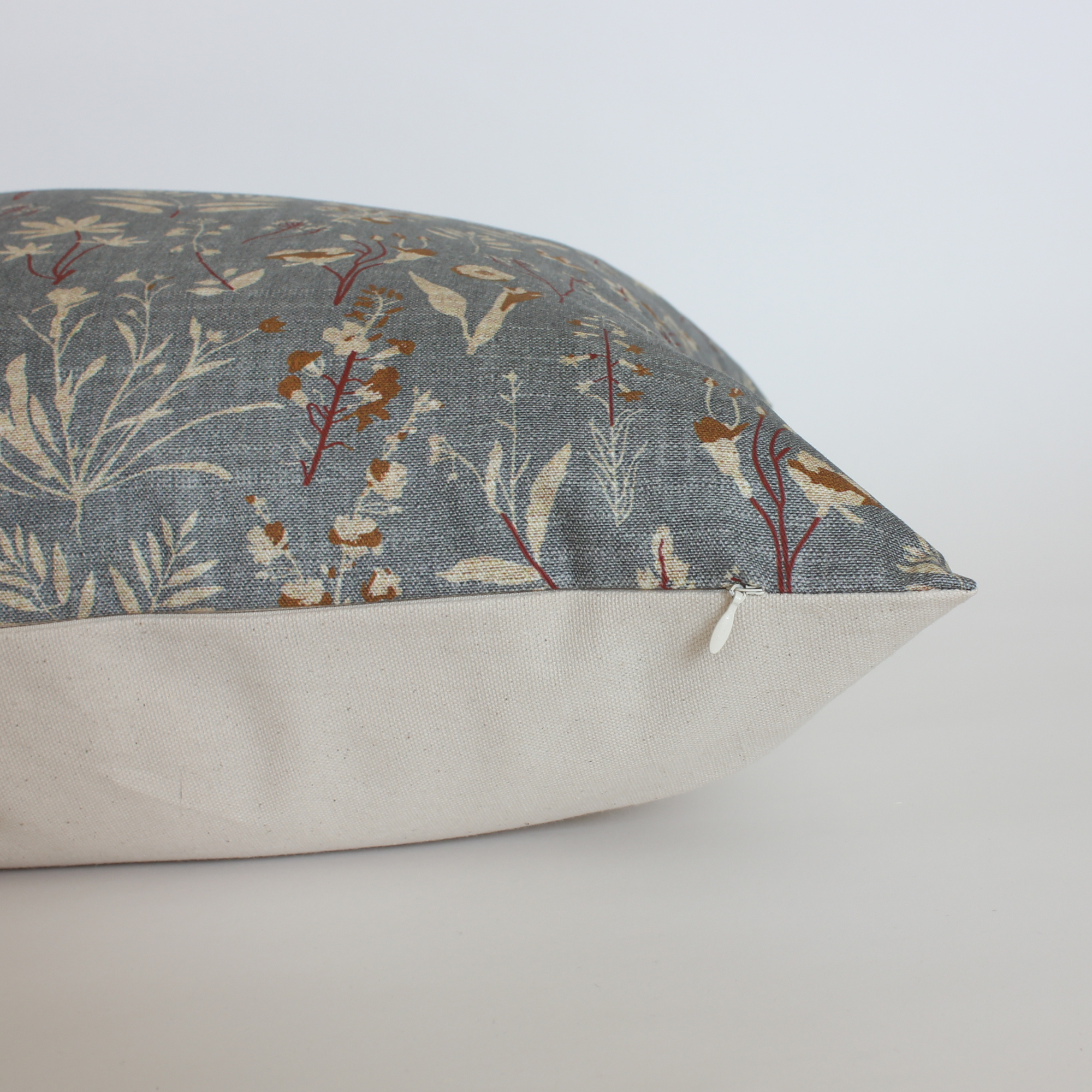 Side view of slate blue floral throw pillow cover showing cream canvas back and hidden zipper closure